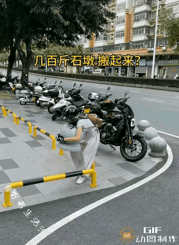 小女子骑着大摩托车，从人行道上下公路，被石墩子拦住了去路。她下车，双手抱走石墩子