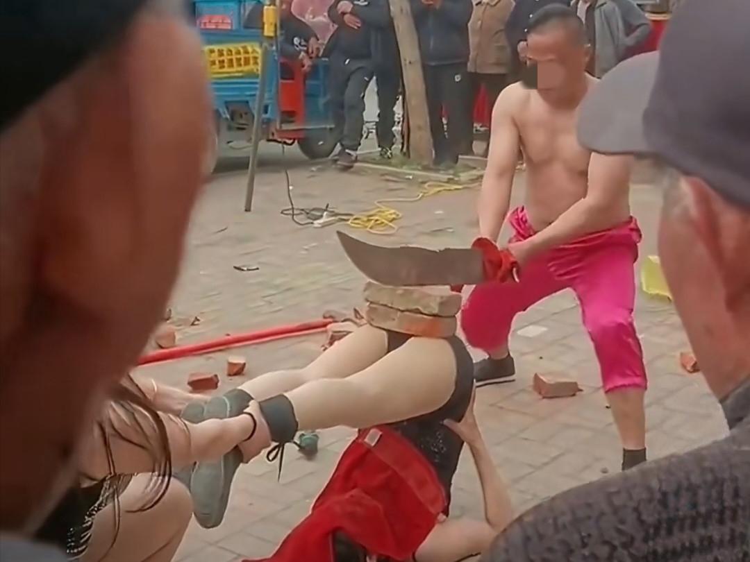 我的天啊！这街头表演也太拼了......

只见一位女子用头撑地倒立，另外一名女