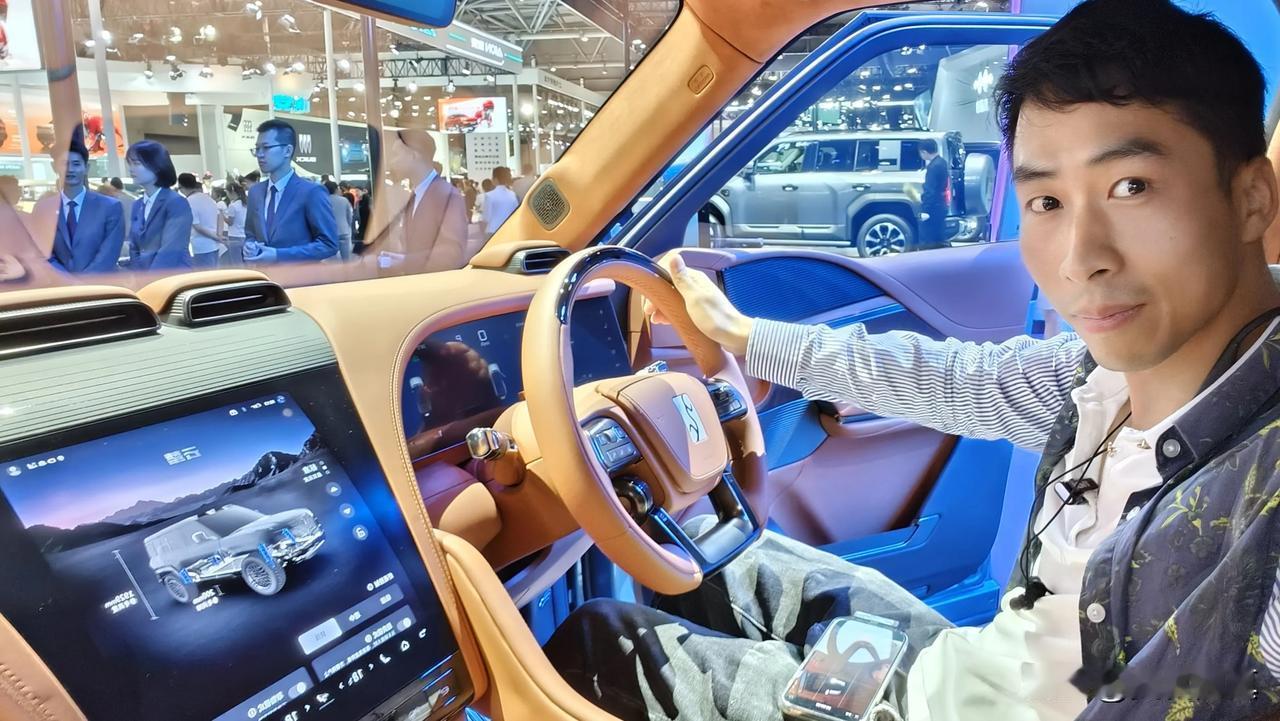 
图片中的男士坐在驾驶座上，显得非常从容。他穿着一件带有图案的衬衫，这增加了他的