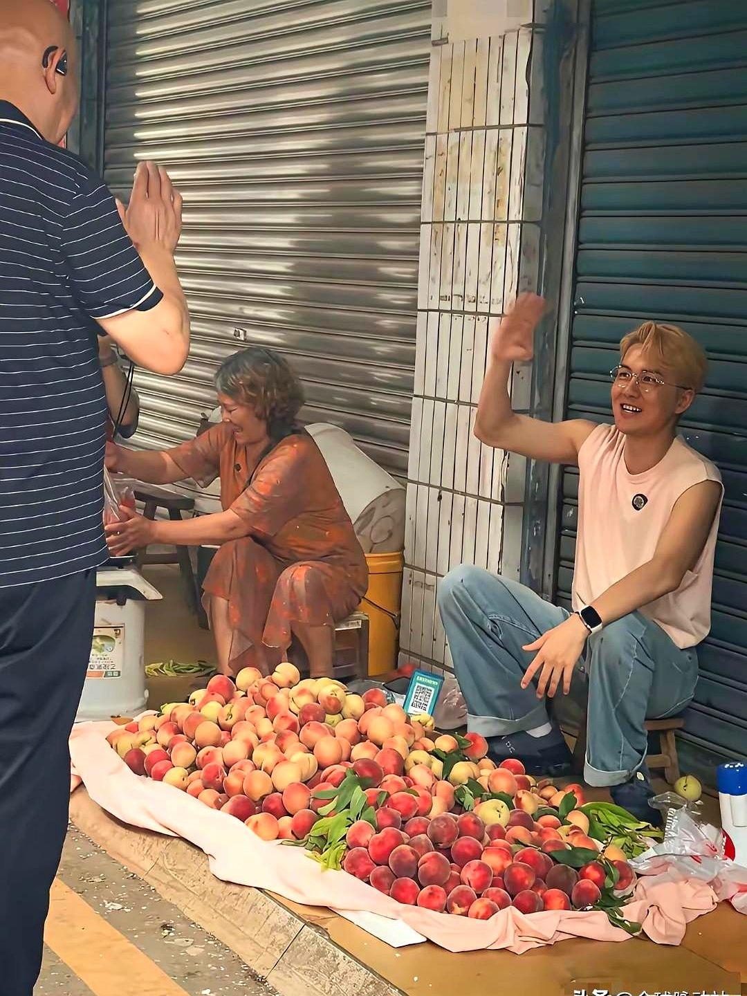 四川遂宁菜市场，一个穿粉背心的大哥火了，蹲在桃子摊前，拿个喇叭扯着嗓子喊“又甜水