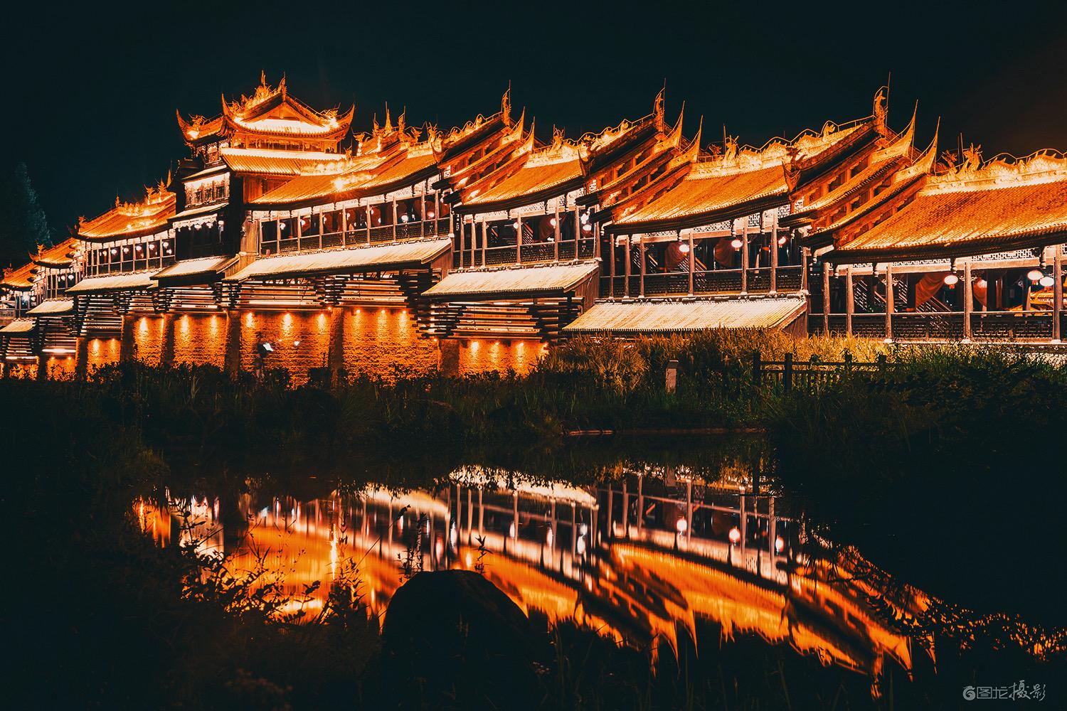 2022年6月，重庆濯水古镇的夜色如墨，风雨廊桥在暖黄灯光的勾勒下，宛...