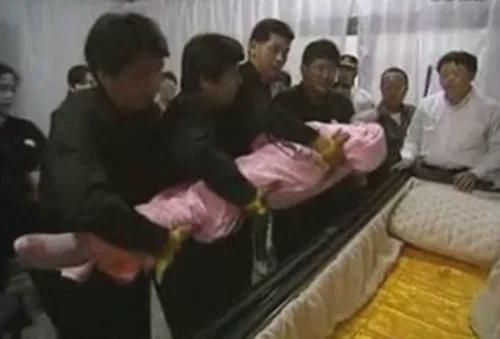 这是邓丽君去世后留下的一张罕见照片，镜头中周围的人正在轻轻地将她的遗体放到灵柩当