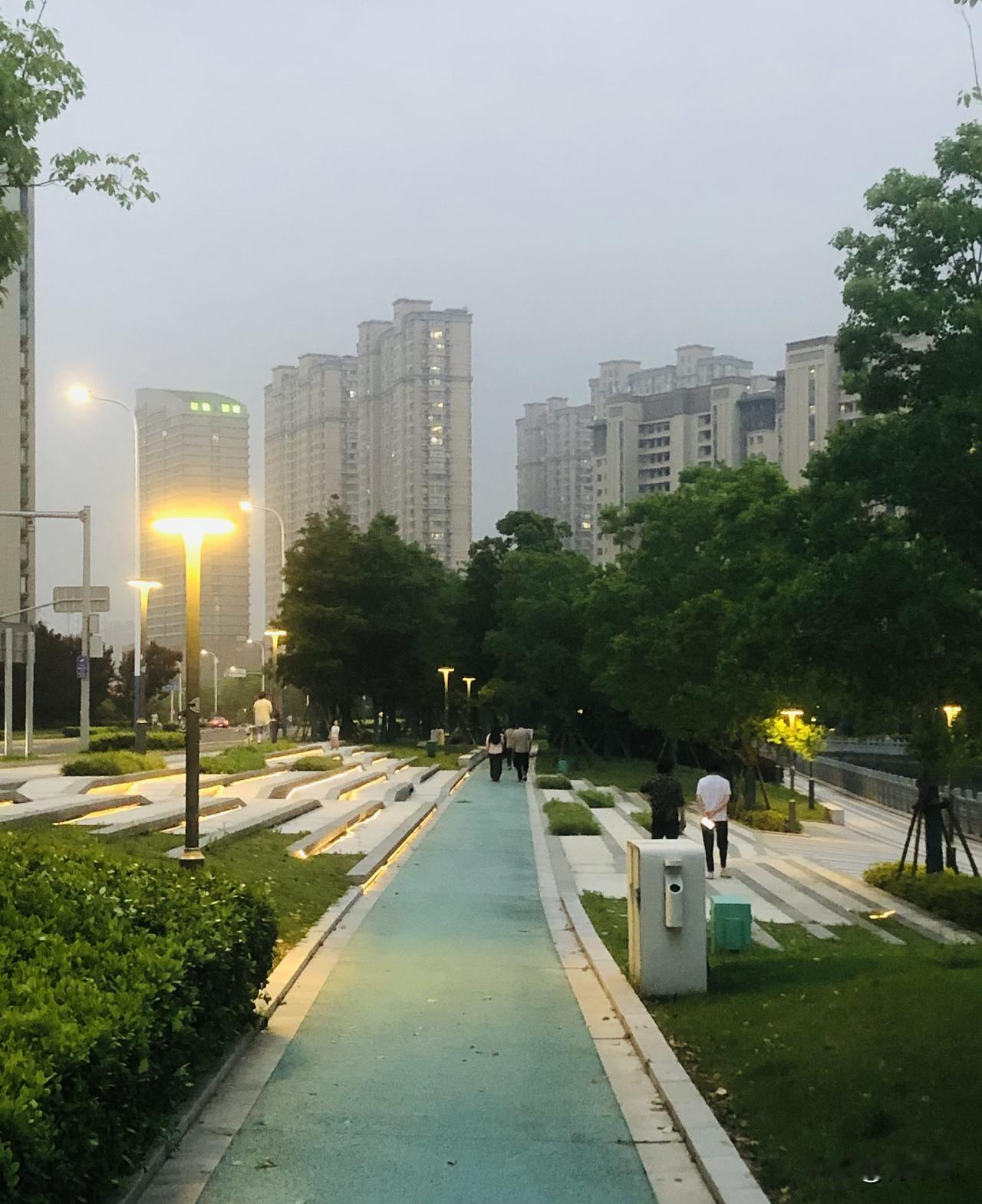 这个是昨天晚上下班后沿途的风景，暮色慢慢笼罩河边步道，路灯次第亮起暖融融的光。有