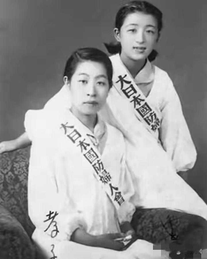 这两个女子身上挎着的条幅比较醒目，尤其是上面的文字，写的竟然是“大日本国防妇人会