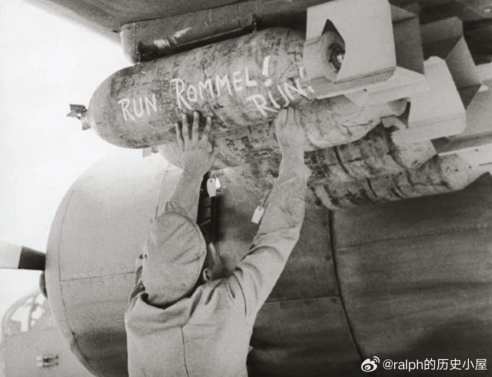 北非战场英军一名地勤给轰炸机装弹，炸弹上写着“Run Rommel隆美尔滚吧”军