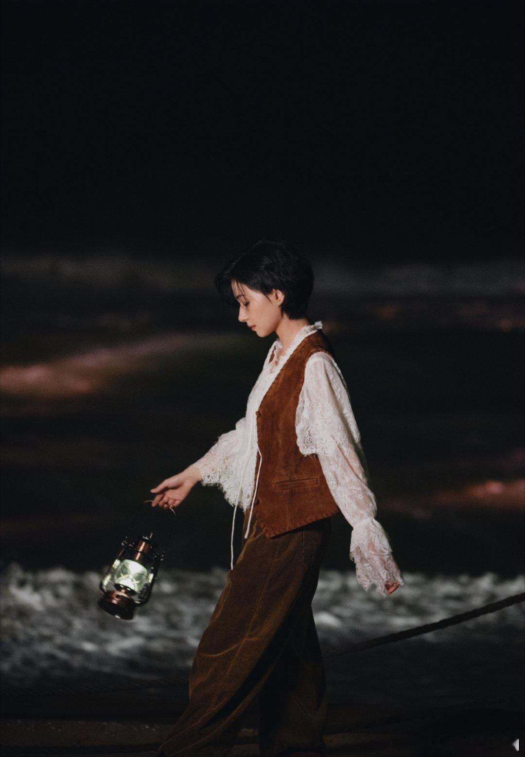 万茜用一盏灯笼点亮海边夜色，复古造型在暖光与海浪间摇曳，一句“藏着第二个月亮”直