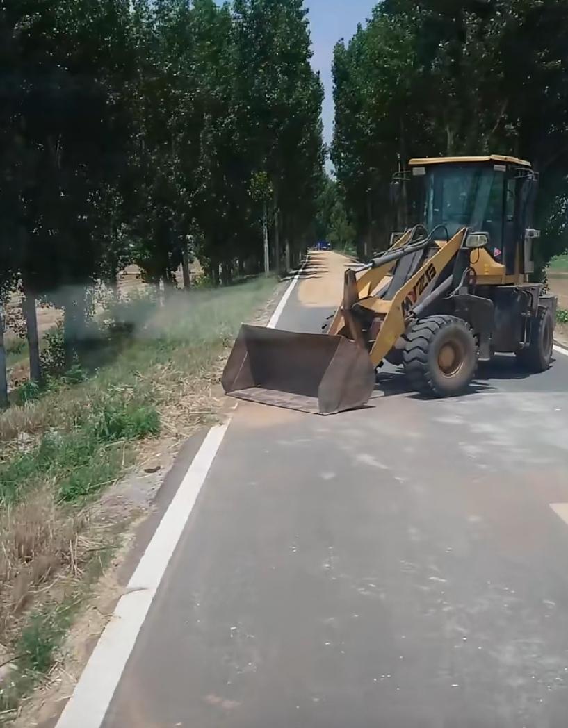6月9日，山东滕州，一乡村道路上，有当地农户为晾晒粮食，直接将一台小型铲车横向停