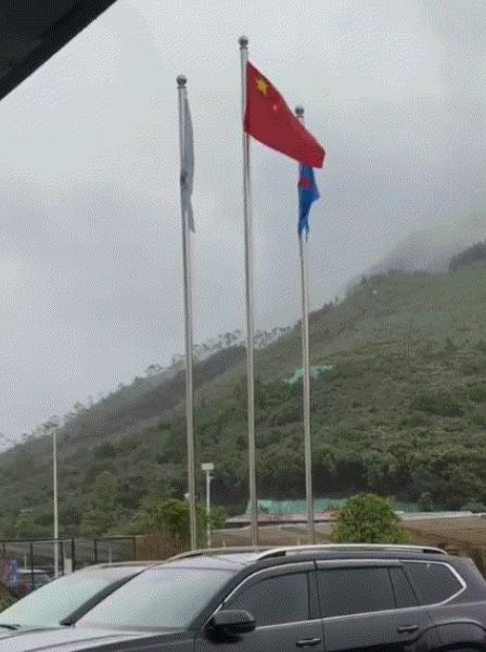 广东，阴雨天里三面旗帜全被大雨浇得耷拉着，男子随口唱起国歌，五星红旗跟着歌声飘了