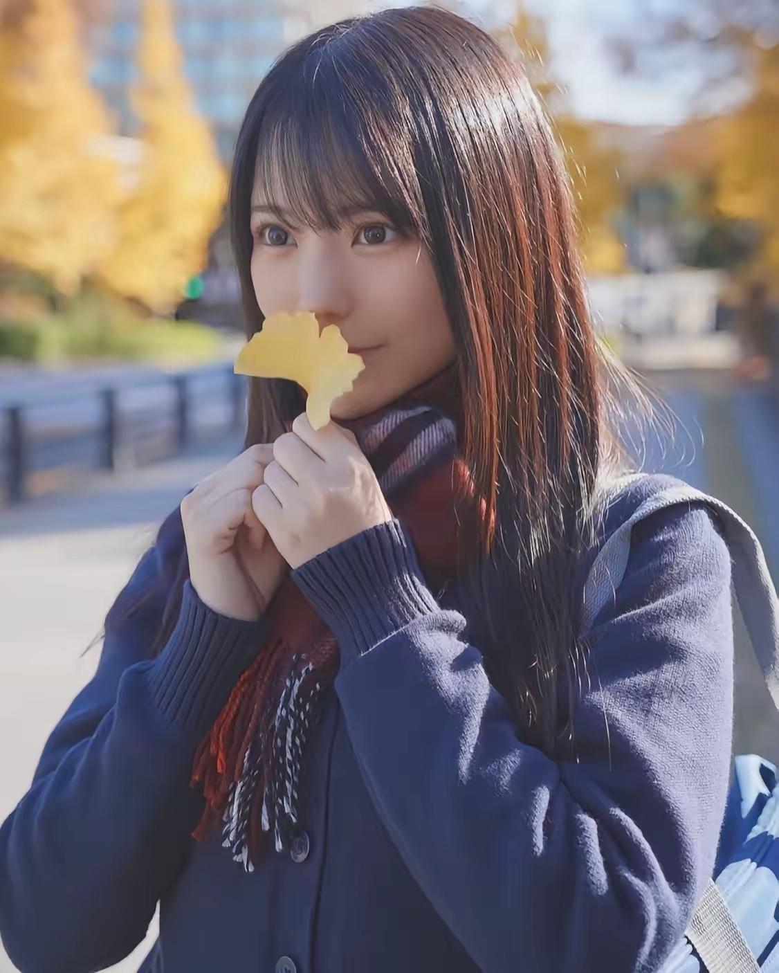 秋日暖阳下，少女轻咬银杏叶，感受季节的温柔。