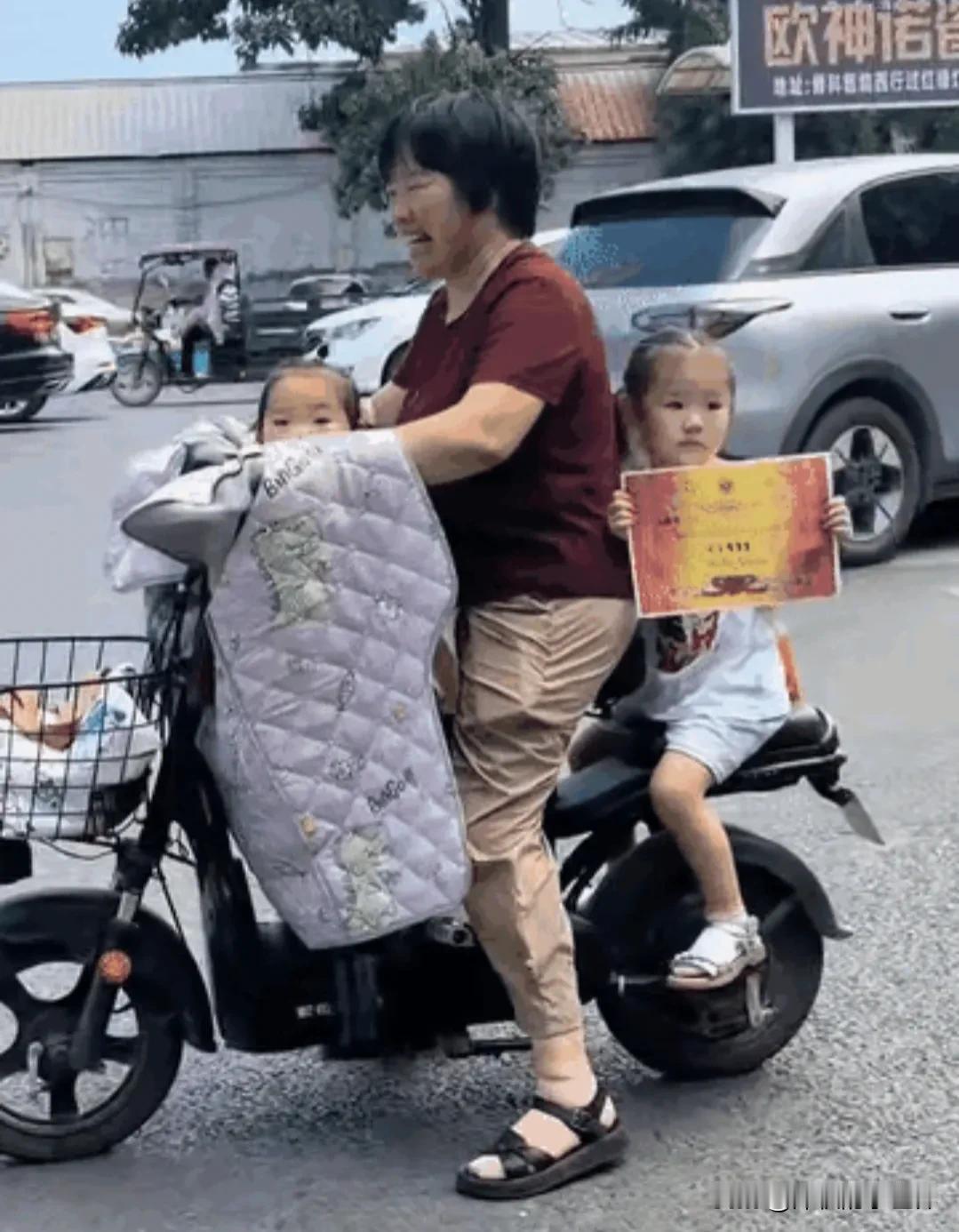 这下全国人民都知道了！

这个小女孩，坐在奶奶电动车座后，一路举着她在学校刚获得