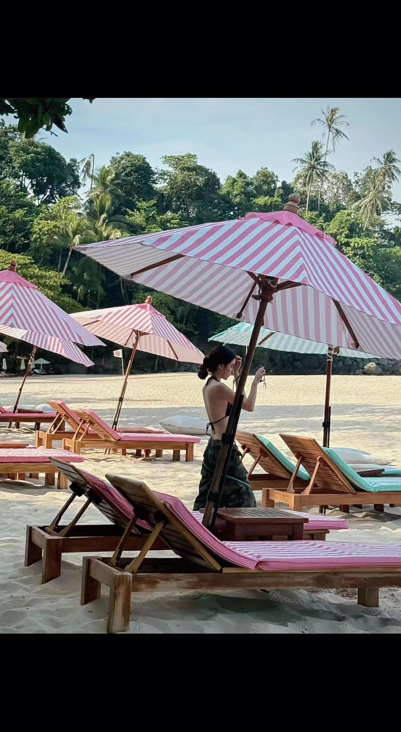 🌴粉白伞像打翻的草莓奶昔，沙粒在躺椅下偷藏阳光✨。风把椰影织成网，网住了谁的未