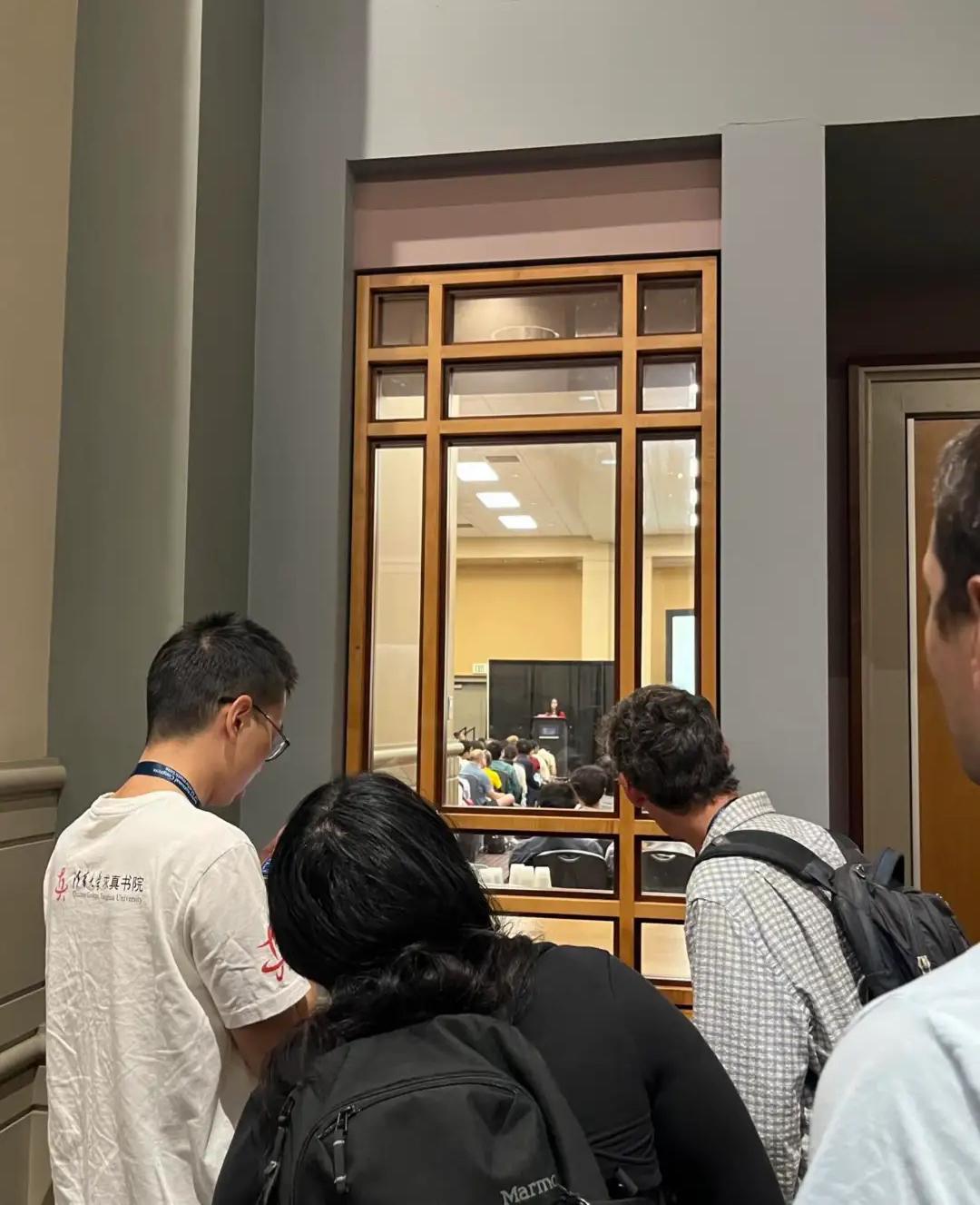 没错，这个挤在窗前王虹演讲的正是她的导师MIT院士拉里·古斯，一件朴素的格子衬衫