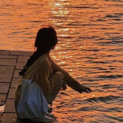 夕阳西下，女孩坐在湖边，静静享受这美好的时光。湖畔风景照 日落湖边景色 湖畔美人