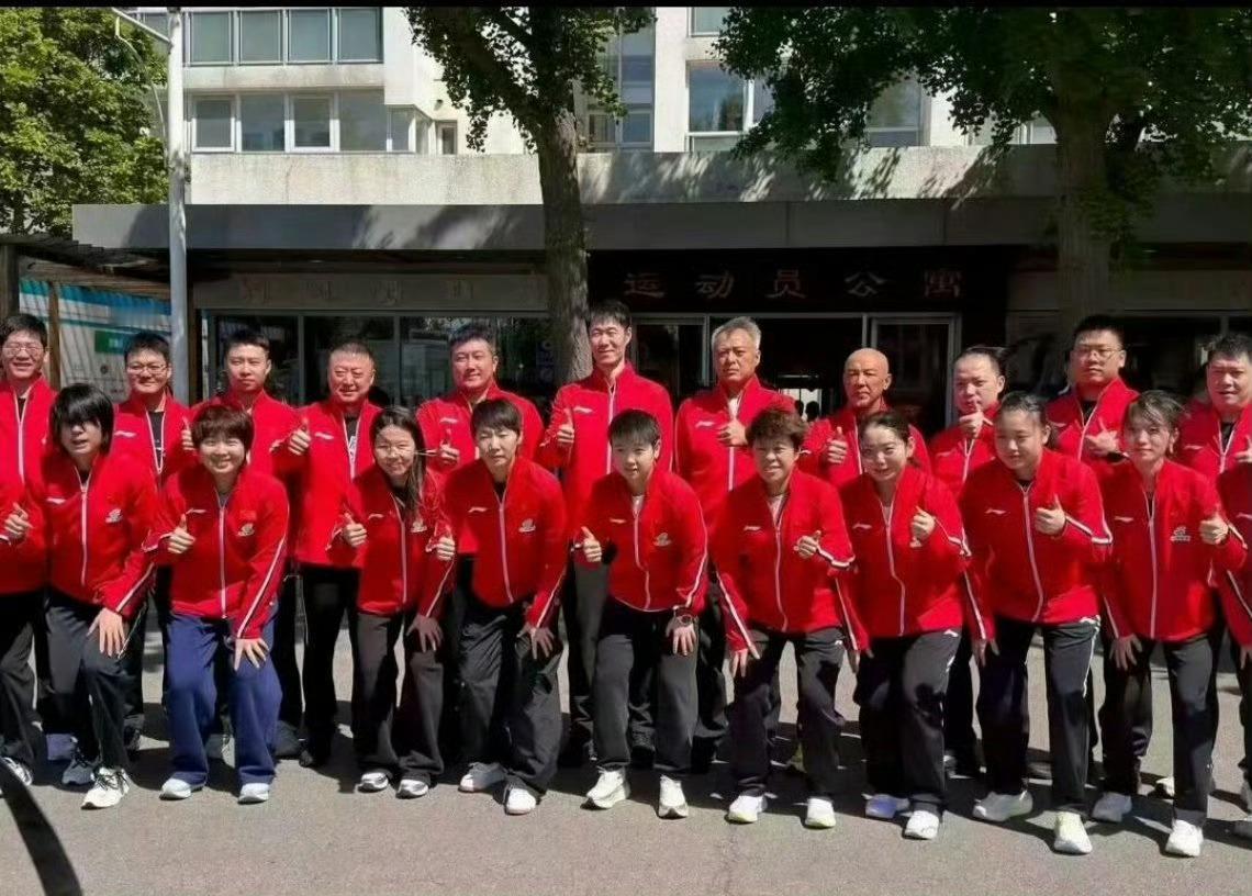 【标题：国乒出征世乒赛合影名场面！陈熠被风吹乱的发型意外抢镜，全员红衣意气风发备