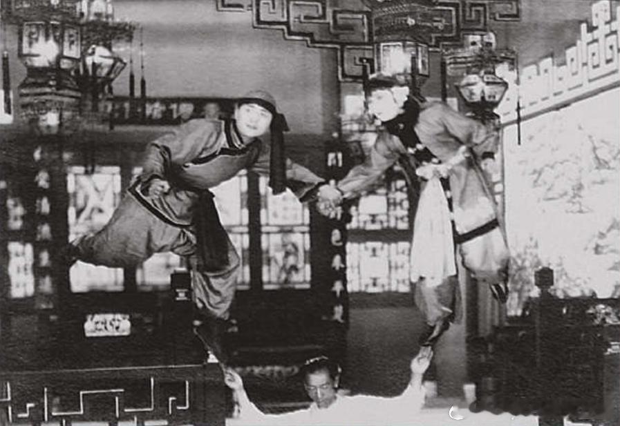 1928年电影《火烧红莲寺》工作照，两名演员身上分别拴着钢丝，下方工作人员把两人