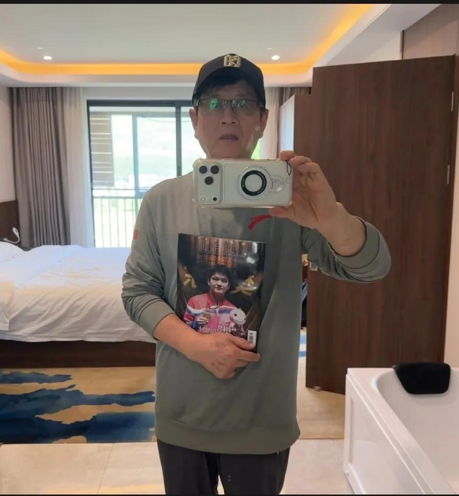 哈哈，吴敬平老爷子又更新了，这次戴上了有樊振东商标的帽子，手里拿着东东的海报，他