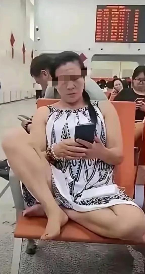 挺老大岁数，穿个吊带裙，光个脚丫子，支个光腿，半盘坐在椅子上，手里捧个手机，一副