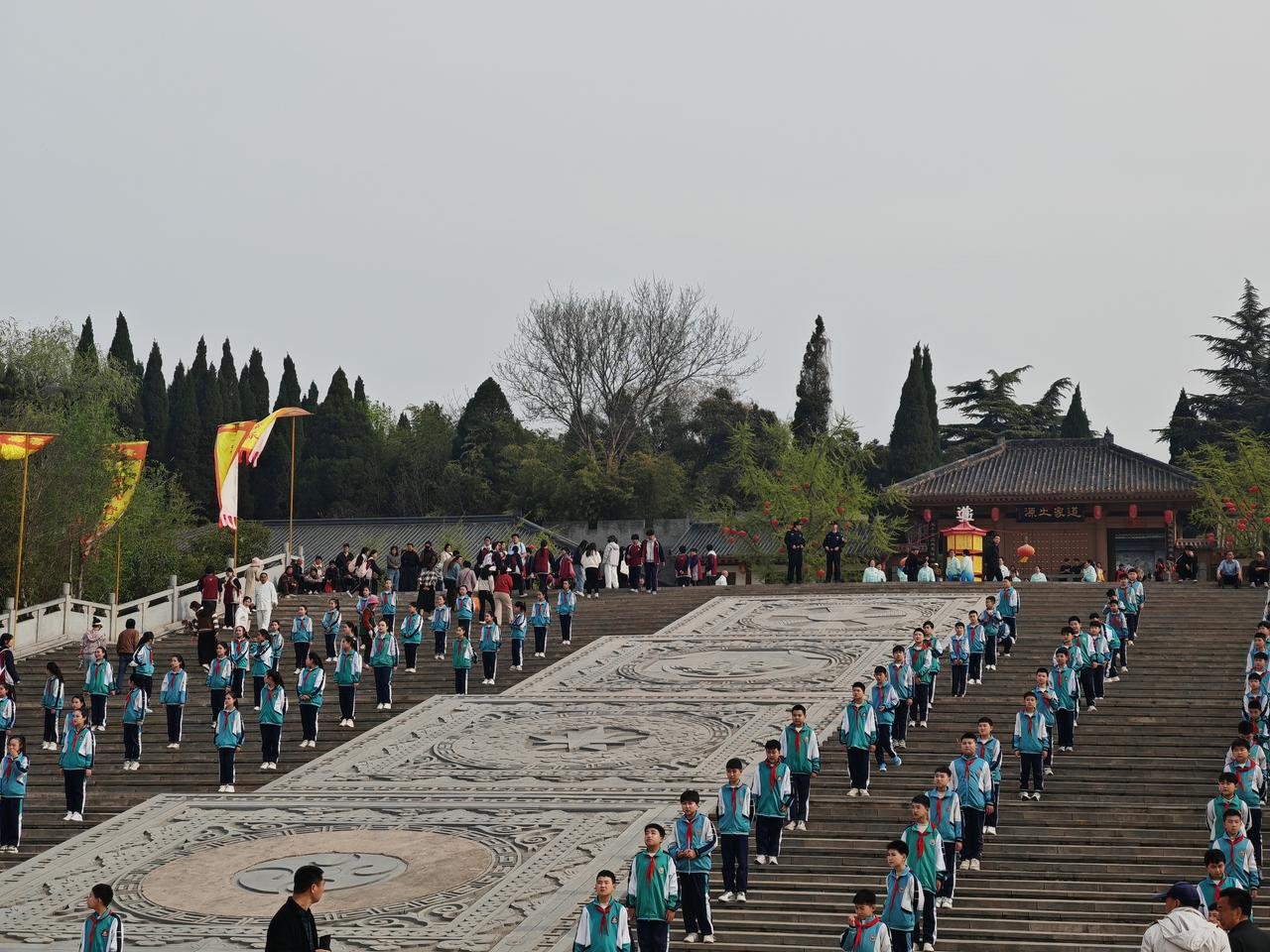 拍摄古镇游玩花絮春日的函谷关研学现场，身着蓝绿校服、系着红领巾的学生们整齐列队，