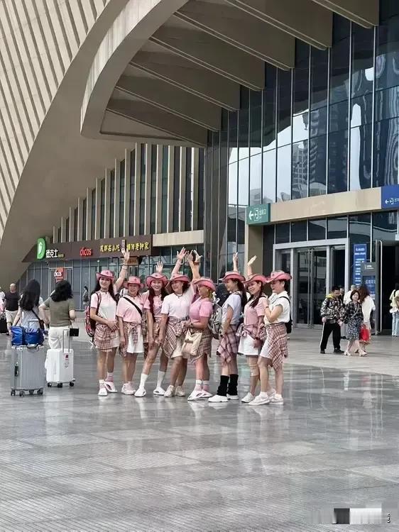 一群中国大妈在某高铁站前的合照，大妈们穿的花枝招展，摆出诱人的pose，看起来精