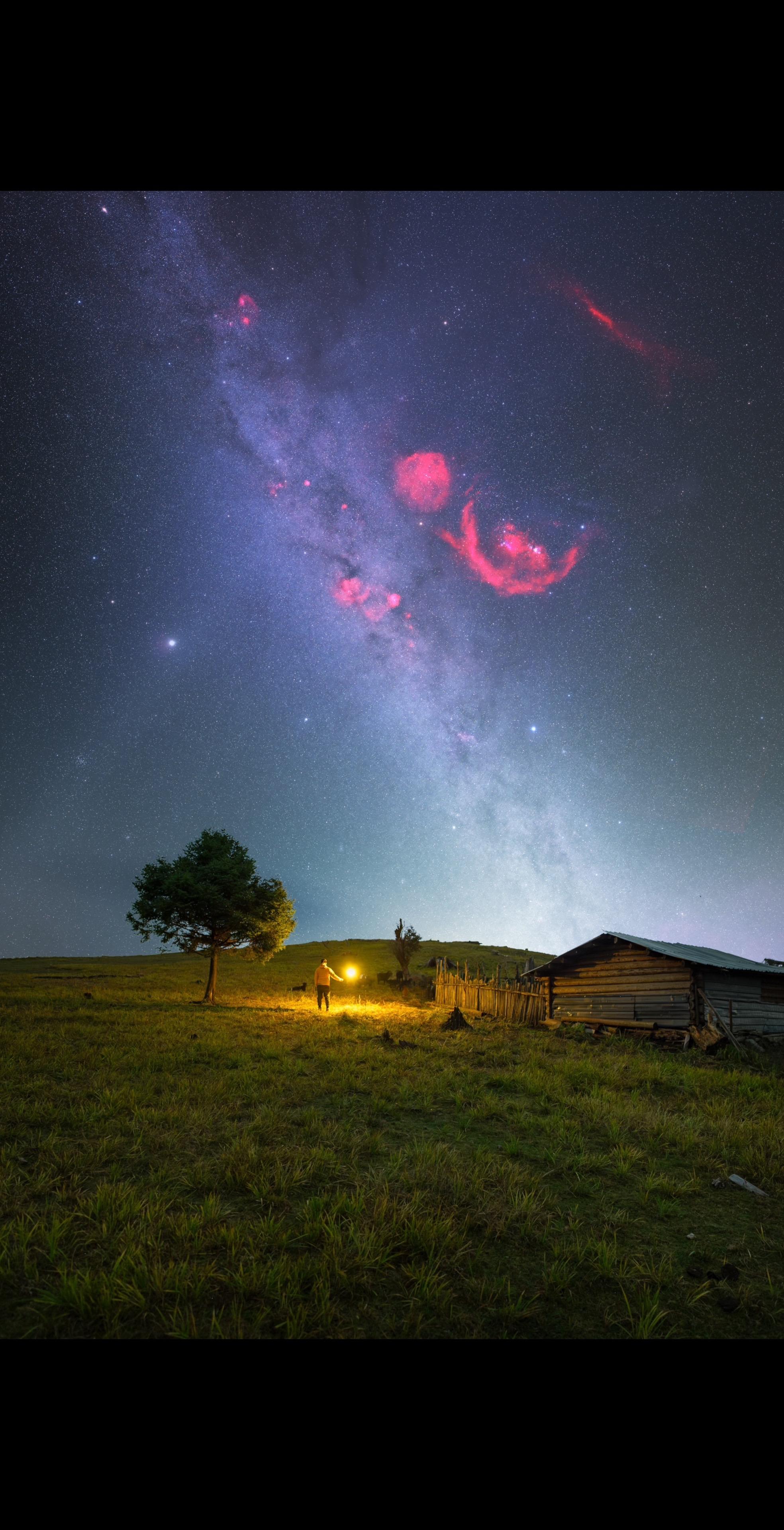 在丽江格拉丹的星空旷野之上。老旧木屋与孤树静默伫立，我手持光源，与这片...