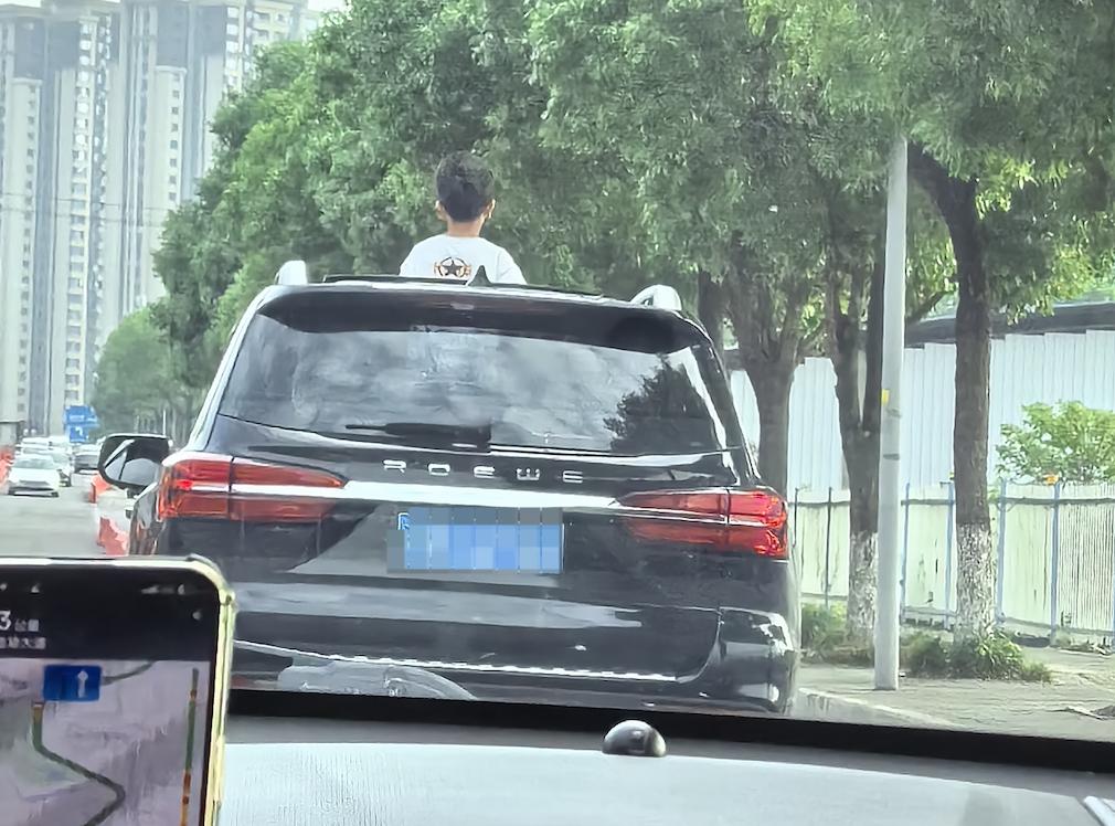 现在的家长，心是真的大，瞧瞧这辆车，居然让自己的小孩探到天窗外面，你就说危险不危