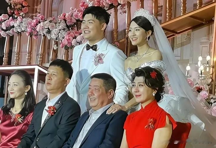 这是闫学晶儿子结婚时的大合影，一对新人笑容灿烂，闫学晶和前夫林越坐在一起，林越感