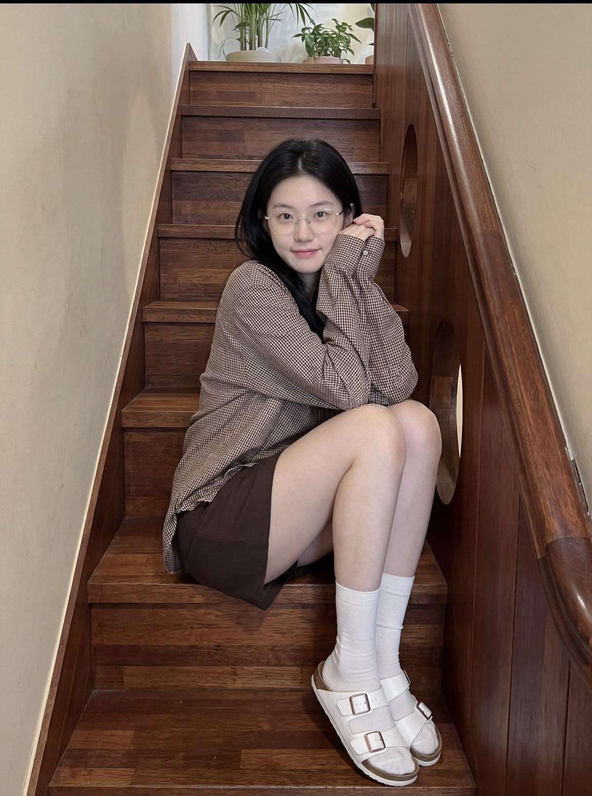 一个女孩坐在楼梯上，微笑着。