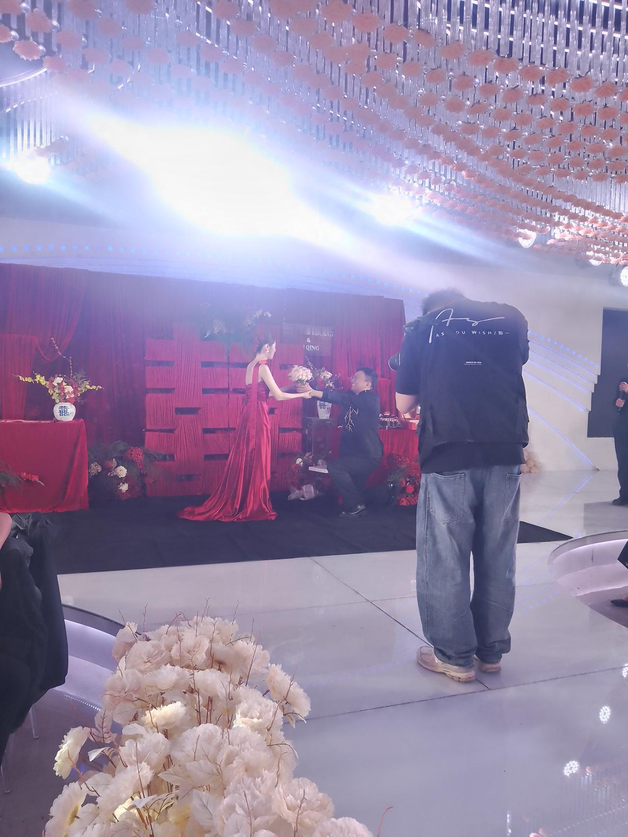 巜七律.贺订婚》
 
红幔高张喜字盈，华堂璀璨映双星。
佳人曳缎含娇立，才子持花