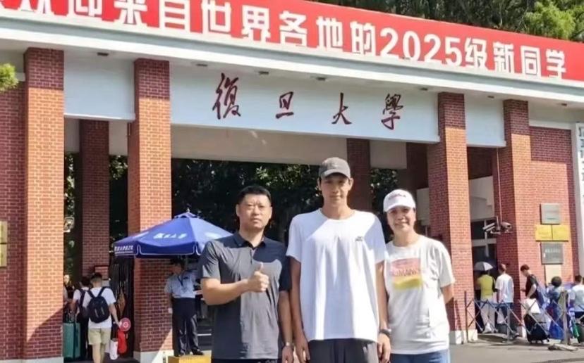 这是2025年张展硕父母送张展硕去复旦大学读书拍下的全家福，其父亲穿着灰蓝色T恤