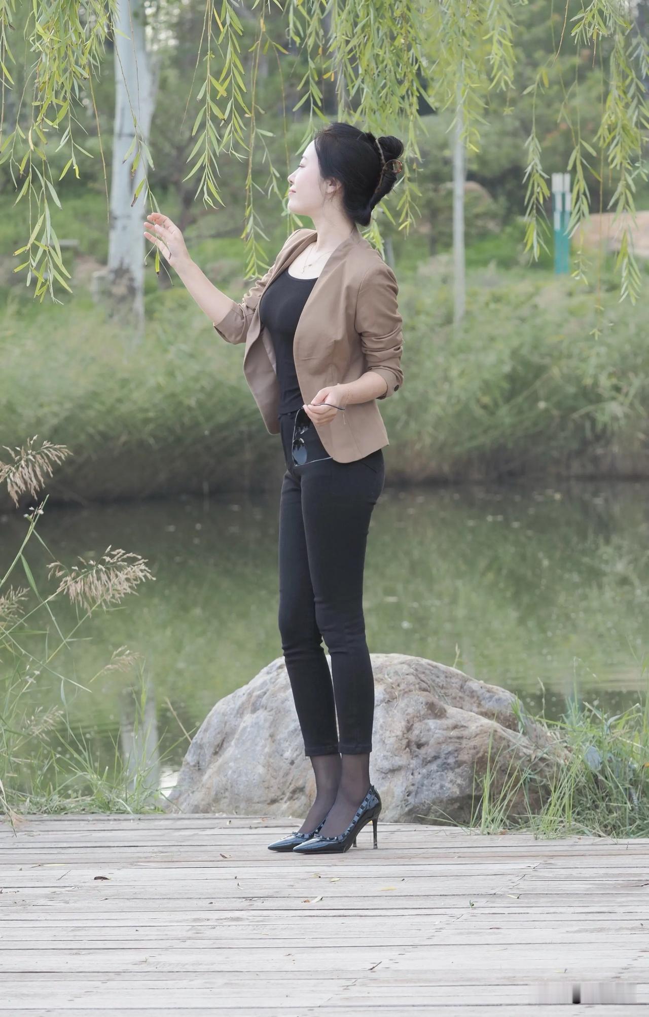 一位女士坐在公园长椅上，看起来好放松。