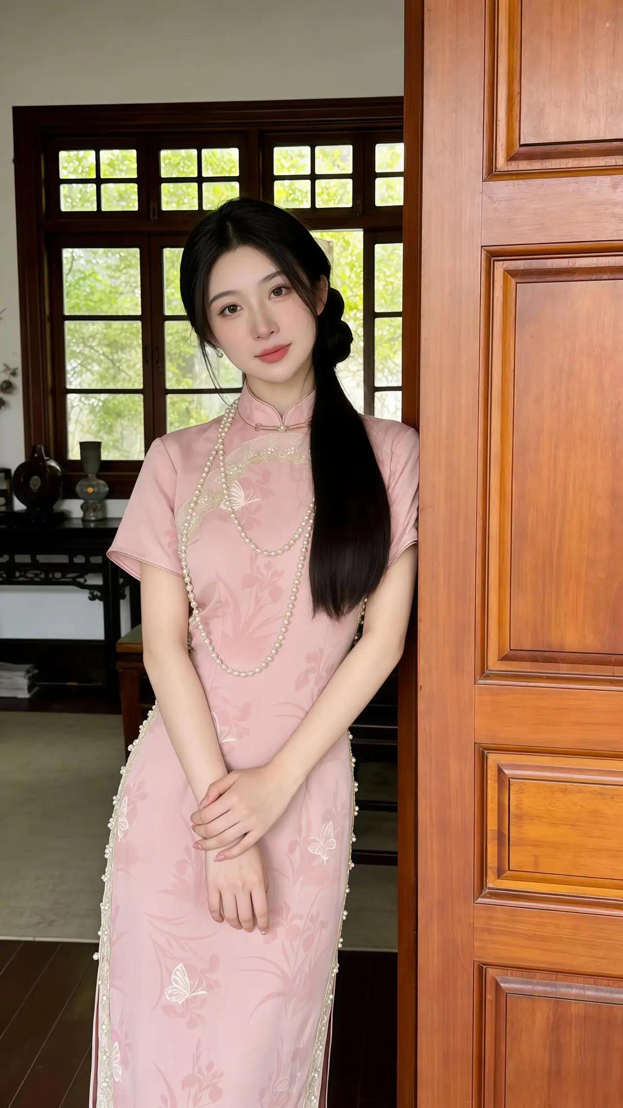 这件旗袍采用短袖设计，领口与开衩处饰有精致的蕾丝与珠饰，裙身印有淡雅的花卉与蝴蝶