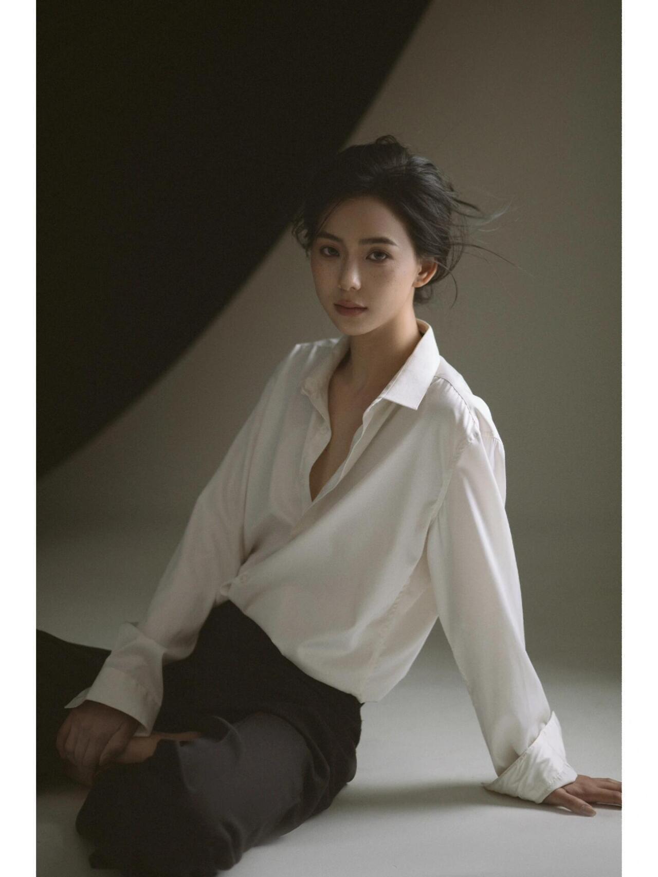 这组人像在色彩与质感的结合上颇具巧思，以黑白灰的低饱和色调构建画面，白衬衫的米白