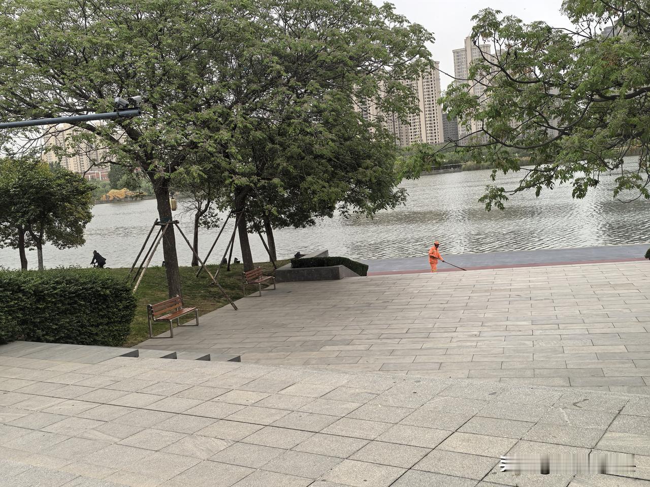 分享一张最近随手拍的照片雨后初晴，看到咸阳湖边一橙色工服的保洁人员正在清扫。湖水