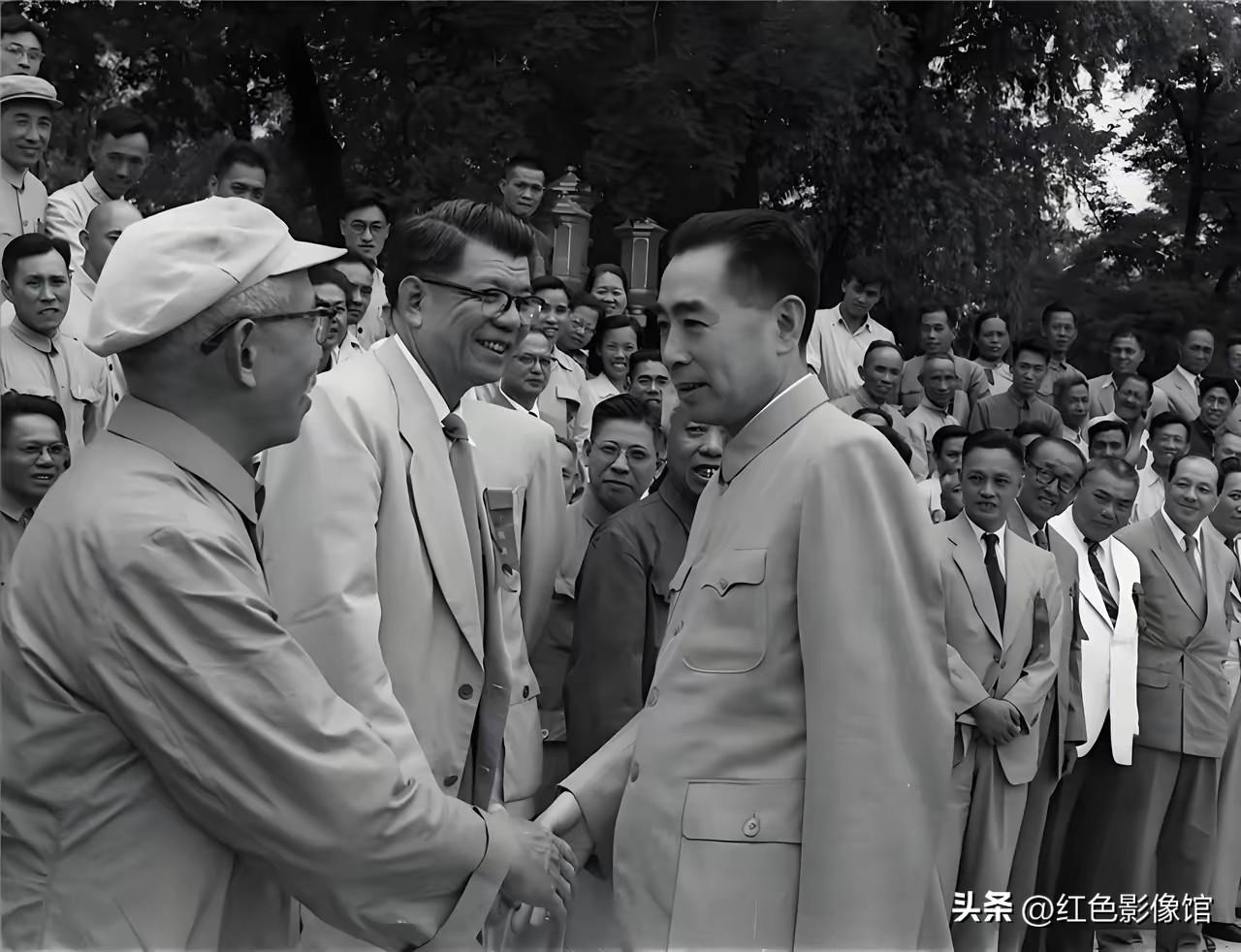 画面右侧人物为周恩来总理，他正与左侧爱国民主人士握手交谈，中间外籍人士陪同见证，