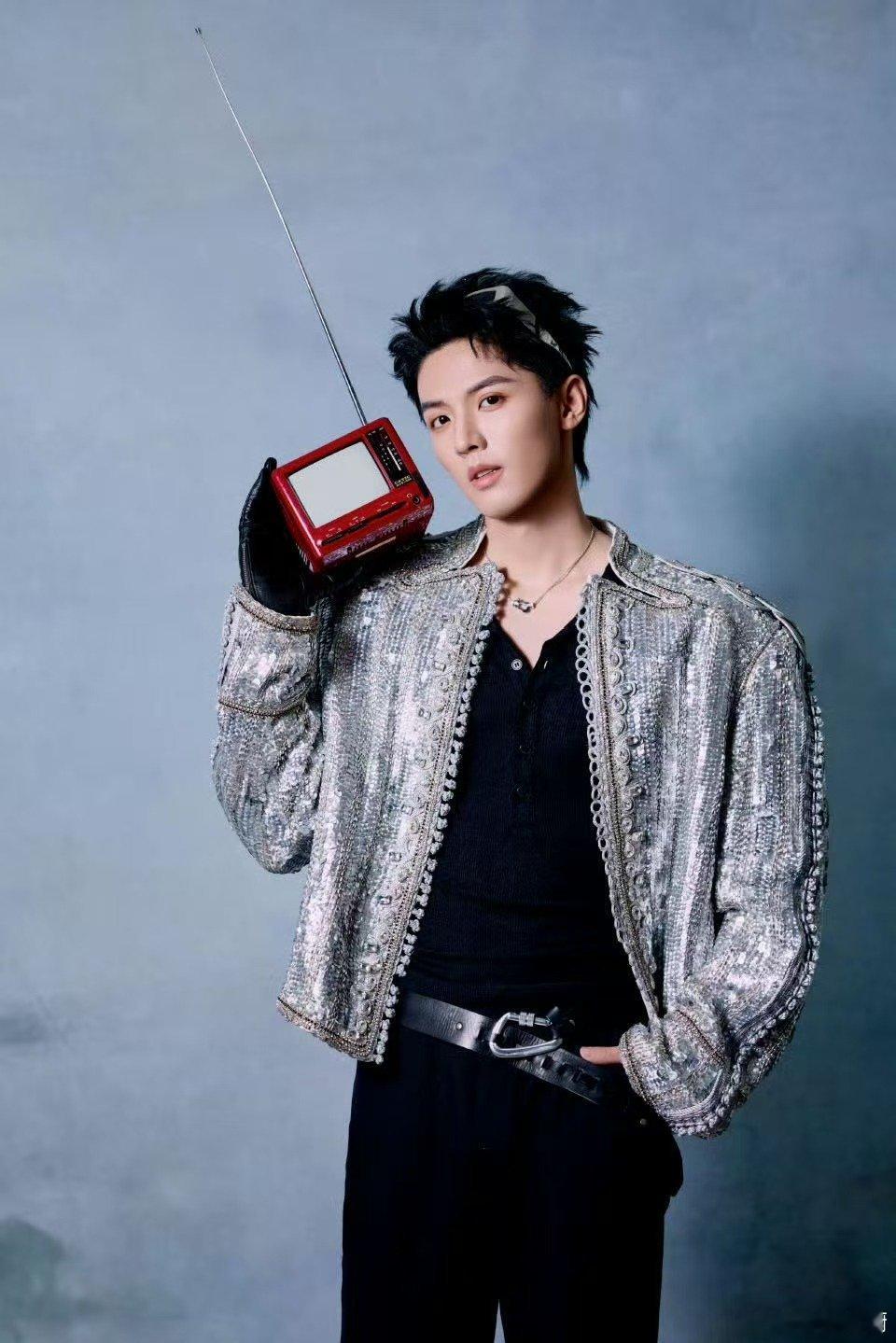 周峻炜银色夹克缀满星子，老式收音机藏着时光的密语。黑手套轻转调频，让复古与未来在