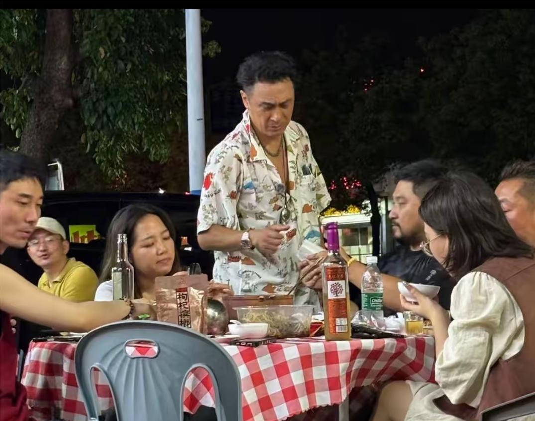 65岁的吴镇宇在广州街边和朋友一起撸串，吴镇宇穿着花衬衣，向朋友敬酒，看样子有点
