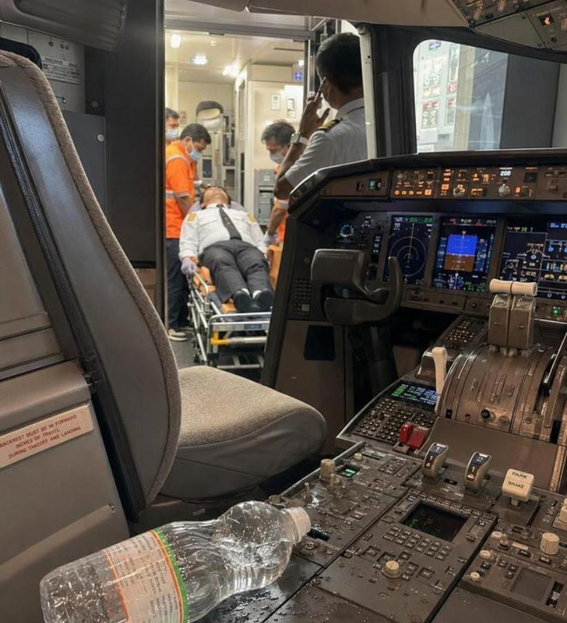 三名脸色惨白、几乎站不稳的飞行员被人搀扶着走下舷梯，随即被送往医院接受进一步检查