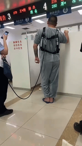 这是网友在医院里拍到的一幕。
一名警察带着一个生病的犯人来医院里做抽血化验检查。