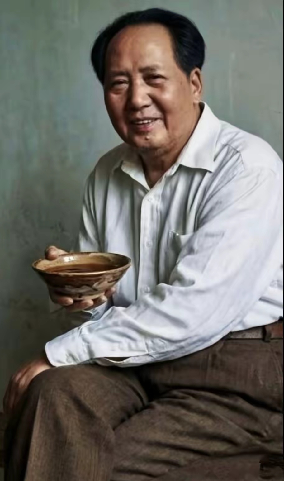 照片里，毛主席身着白衬衫与布鞋，手执粗陶茶碗，神情温和从容，尽显平易近人的气质，
