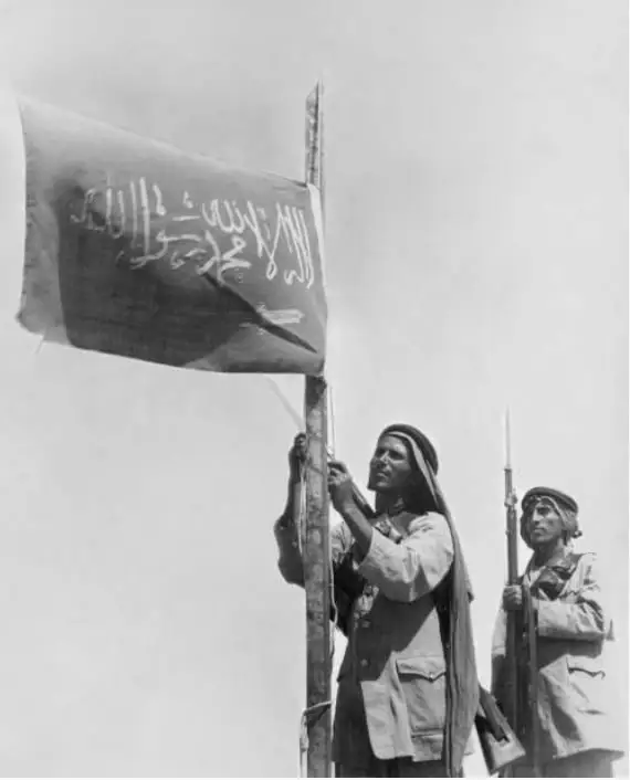 手持国旗的阿拉伯士兵，沙特阿拉伯，1936 年。