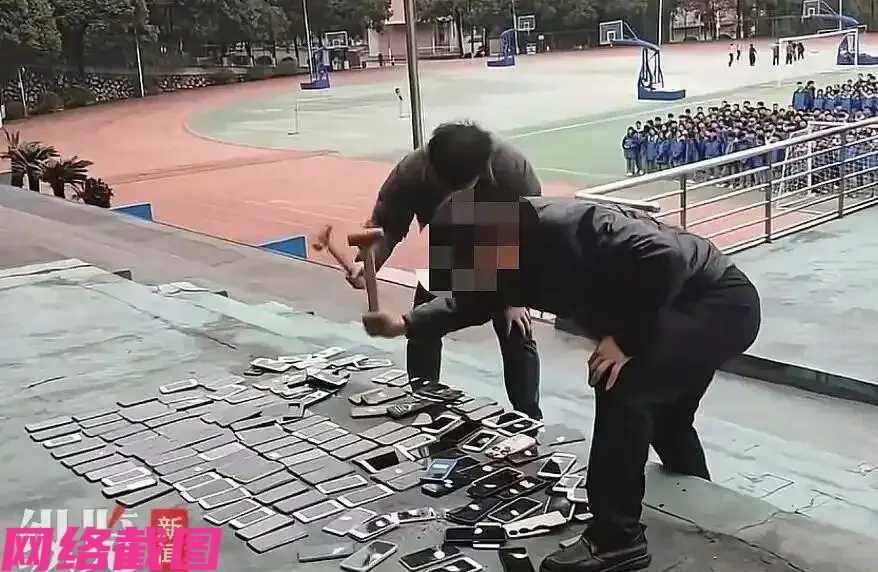 湖南某学校的两位男老师，在学校的主席台上现场手拿铁锤，对着地面上存在的没收来的上
