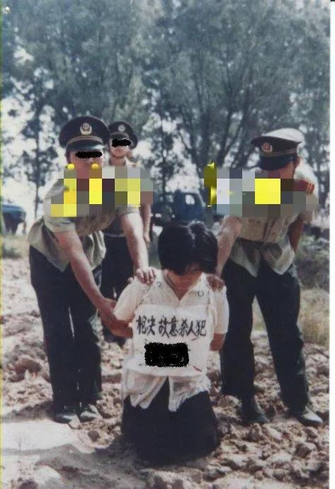 90年代，郊外刑场，一名死刑犯即将被执行死刑的镜头，照片中的她跪在地上，把头垂得