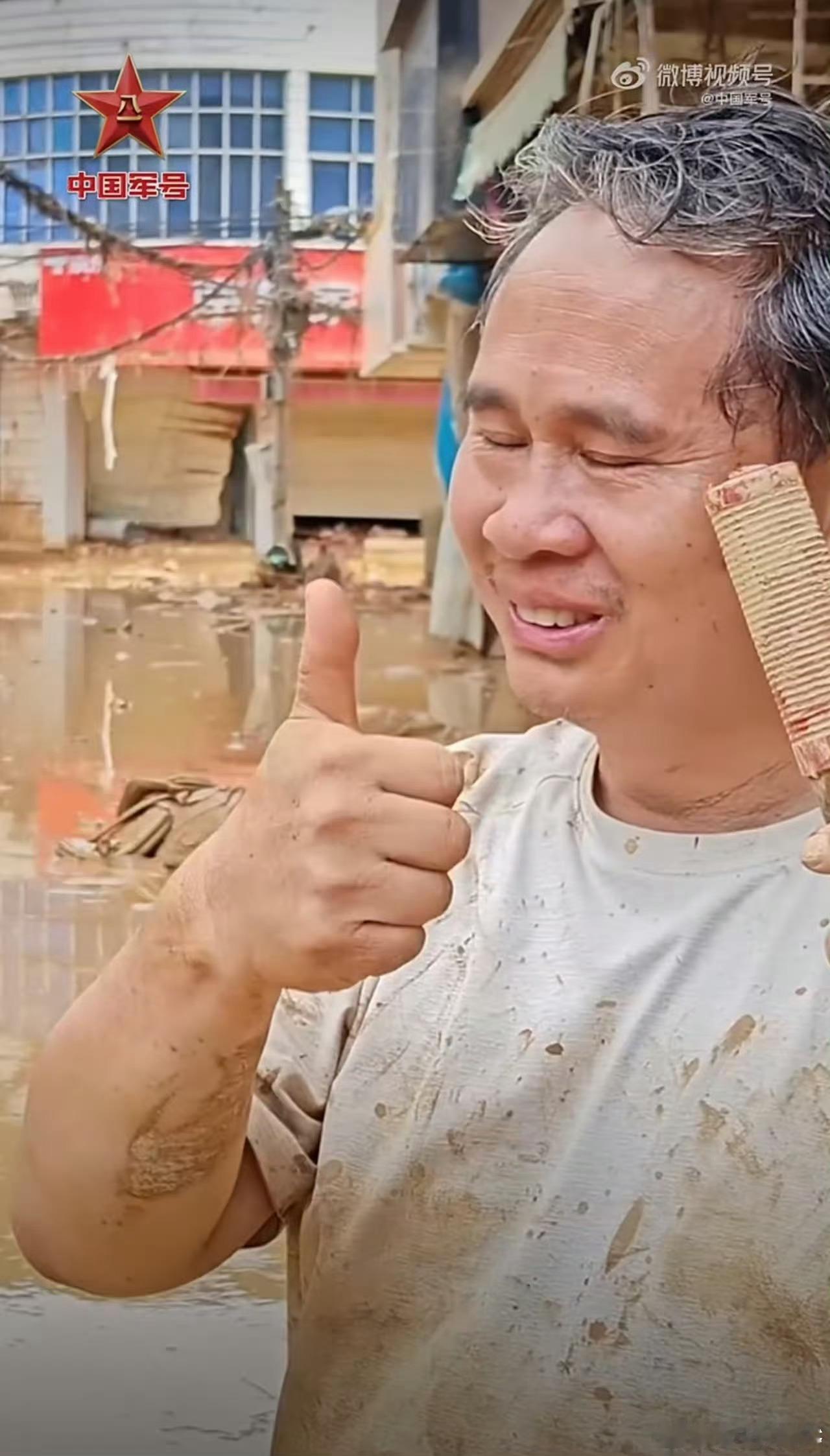 清淤现场村民朝子弟兵竖起大拇指在广西横州洪水退去的淤泥中，村民廖先生红着眼眶朝武