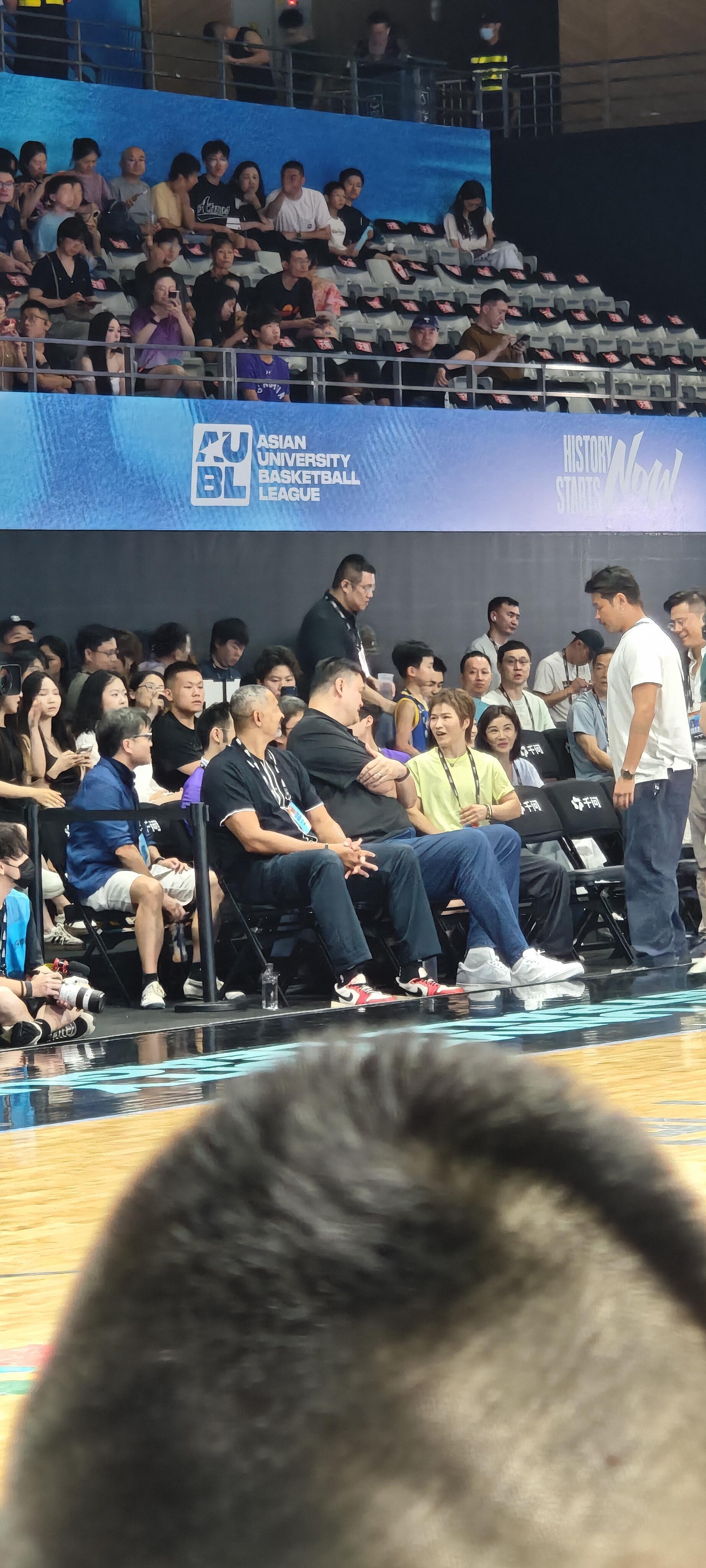 姚明张伟丽同框看球姚明张伟丽邻座观赛 男篮传奇和UFC冠军坐在一起看大学生打球，