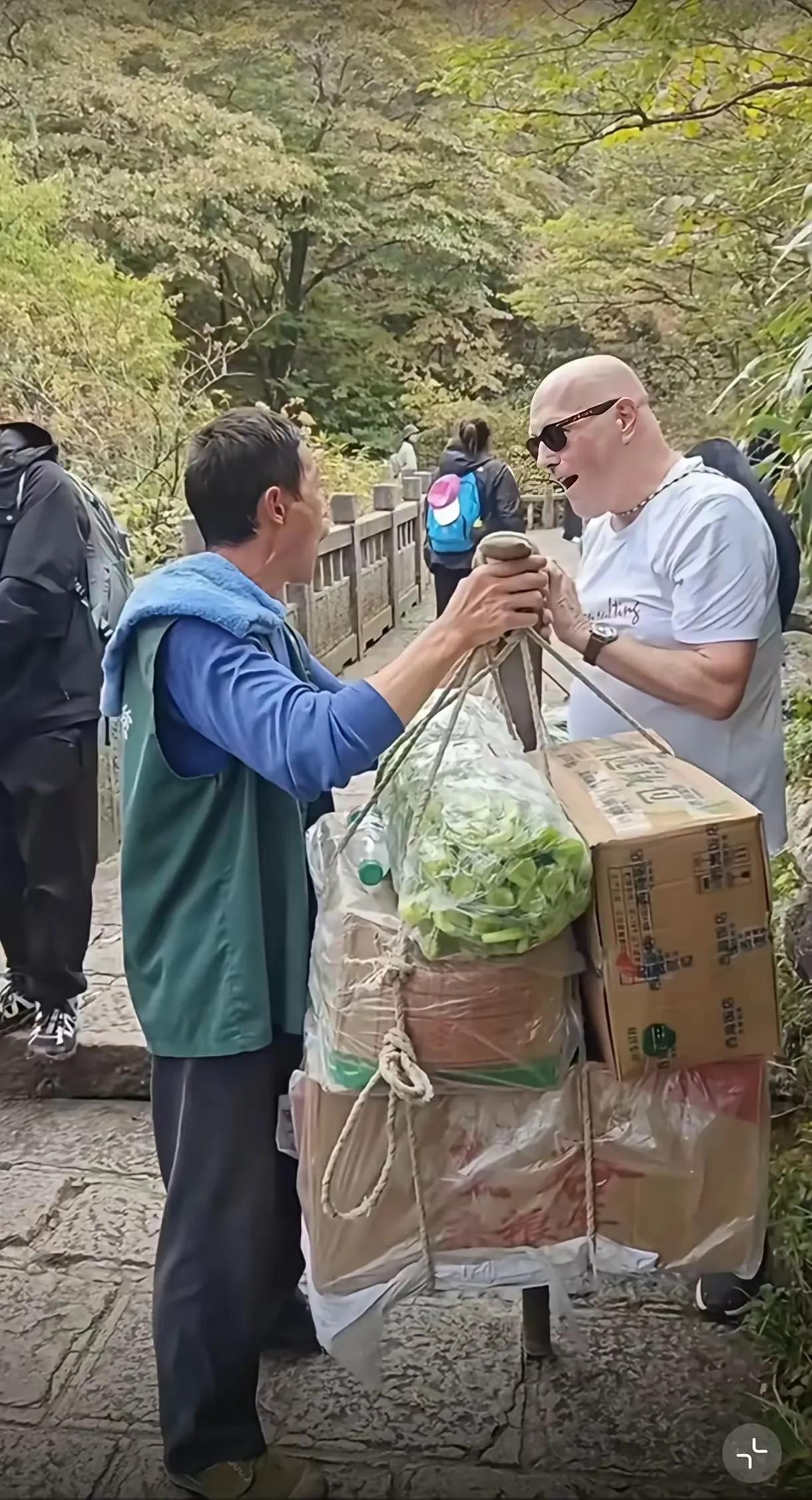 在景区一位外国游客看到中国挑夫挑了这么多东西，他也想试试看能挑起来不，结果他挑了