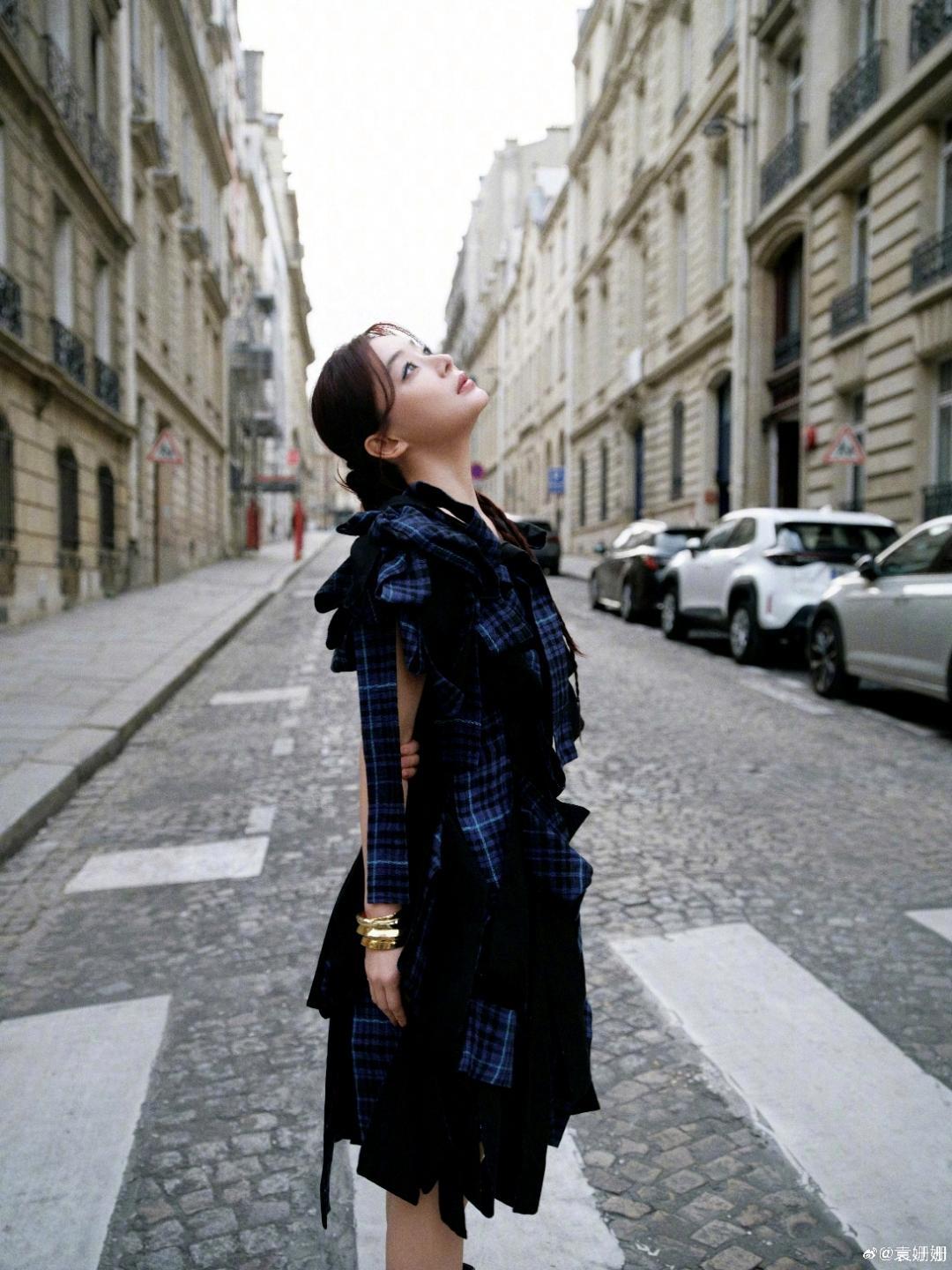 背景里的欧式石质建筑、木质大门与巴黎街道完美融合，袁姗姗或侧身凝望远方，或倚门而