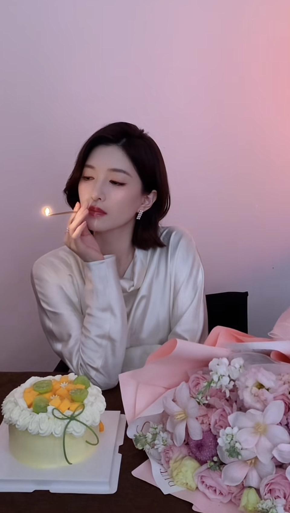 一个女孩在吹蜡烛，旁边有花。