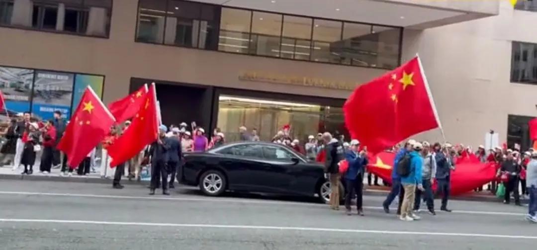华盛顿街头民众手持中国五星红旗、美国国旗走在街头参加欢迎活动。