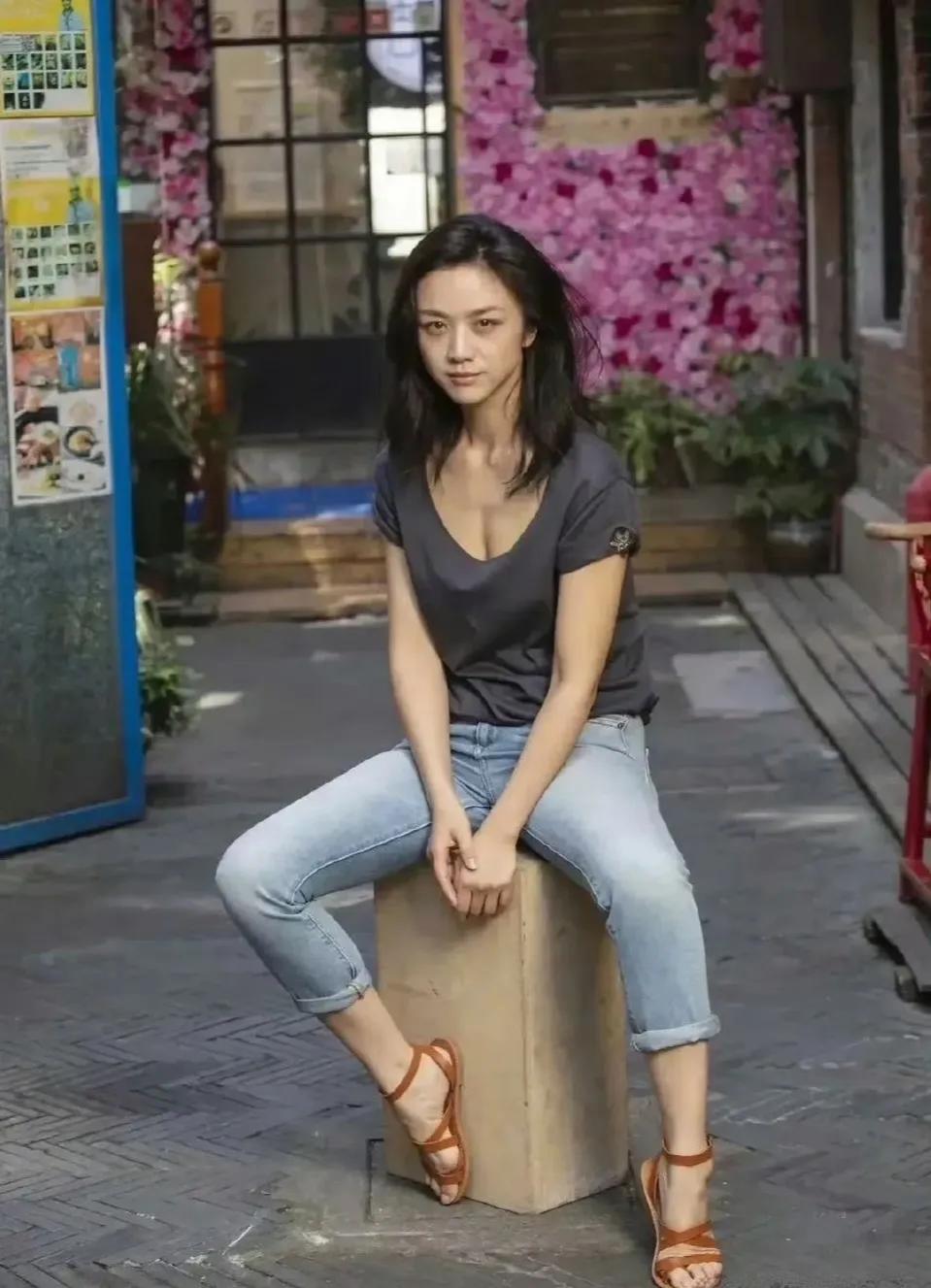 汤唯这霸气随性的坐姿，在配上这随意的背景，感觉就向摆路边摊的小商贩外等着别人买东