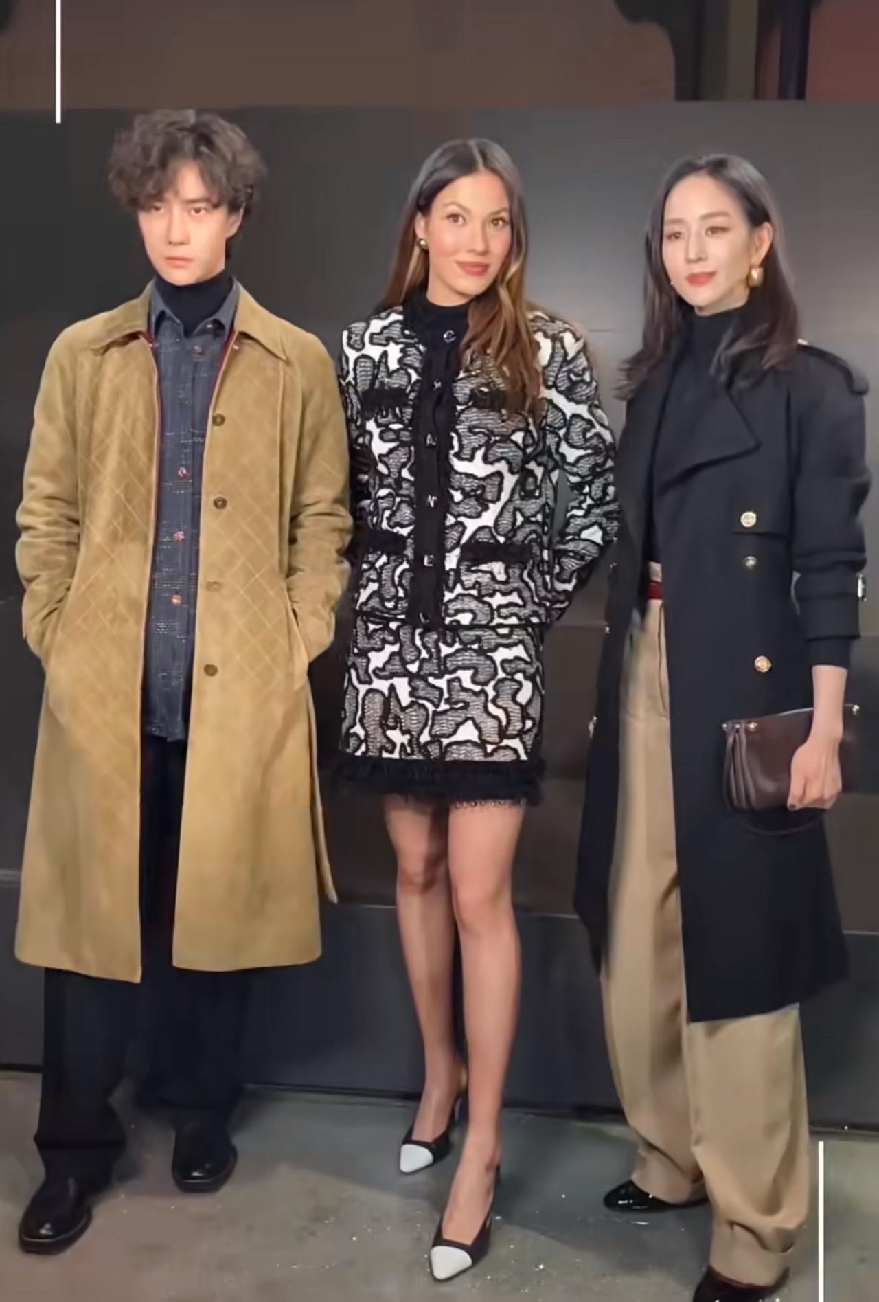 三人合影，有点意思。

一个是43岁，黑风衣飒到起飞；一个是22岁，黑白印花套装